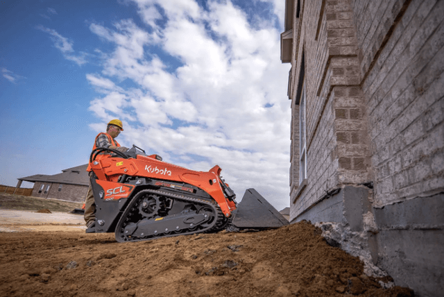 SCL1000 Man using a stand-on compact loader on construction site