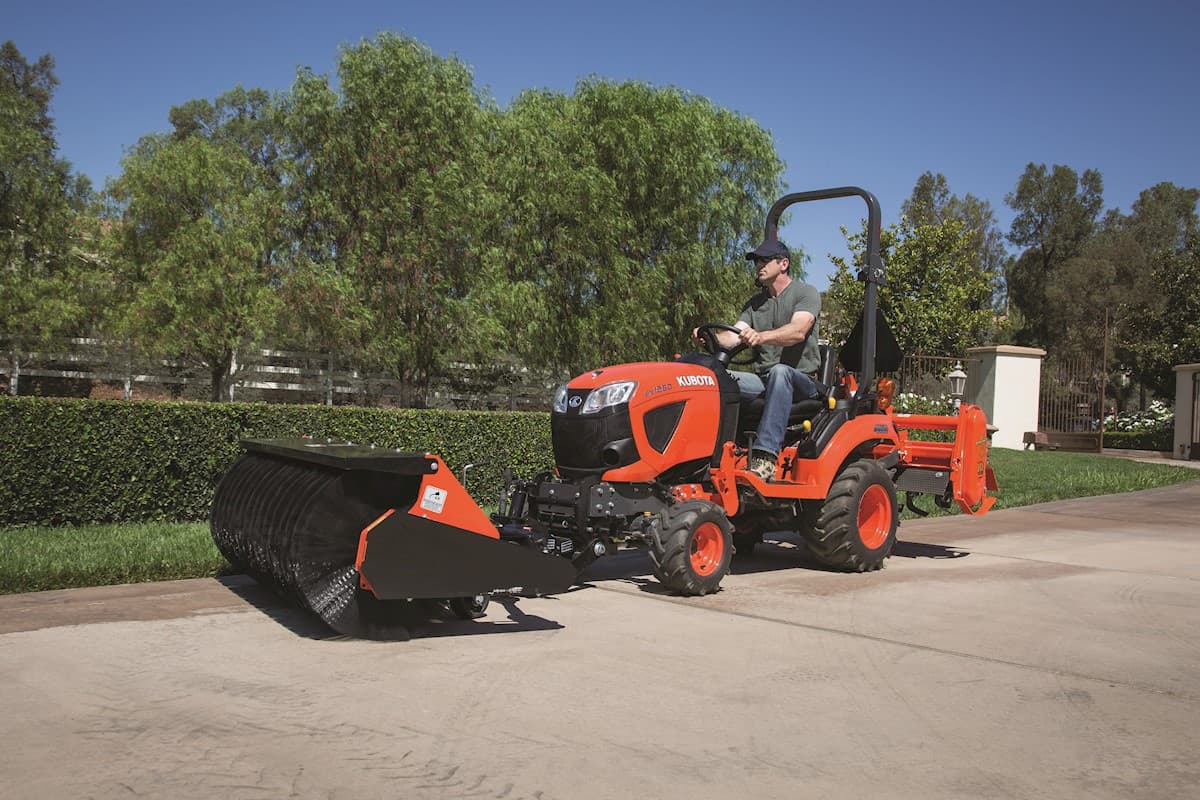 Man using his tractor with sweeper attachment