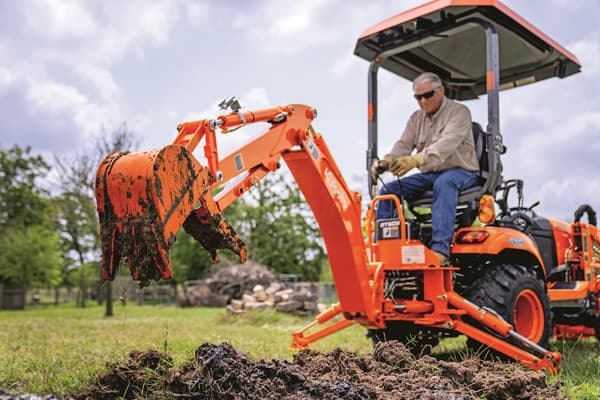 Man using rear back hoe on tractor