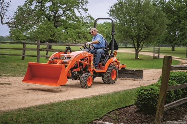 Man leveling out driveway with blade rear attachment