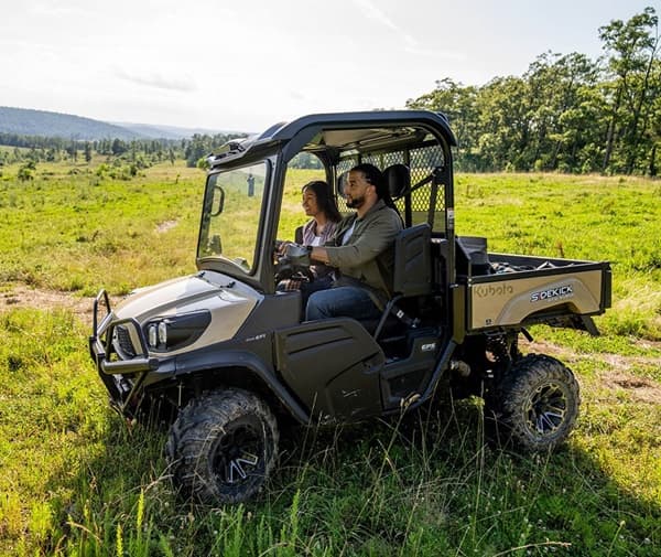 Couple driving through grass with an RTV