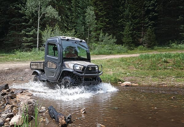 RTV driving through a shallow pond area in the woods