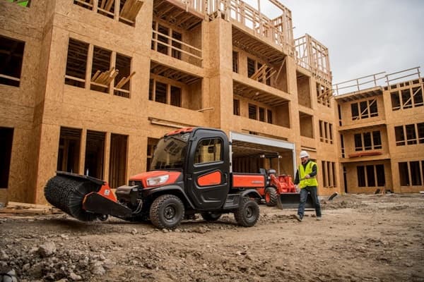 RTV on construction site with a front sweeper attachment