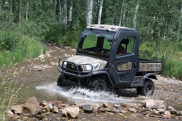 RTV driving through water and rocky terrain in the woods