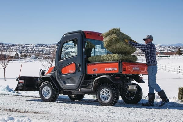 Man loading up cargo bed with hay stack